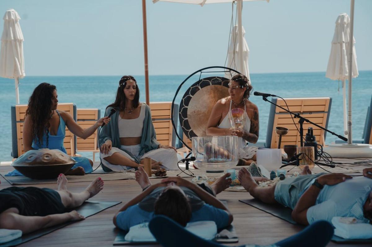 A beachside sound bath at Costa Palmas, guests resting on mats above the water